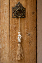 Handgefertigter Wand-Pompon aus Kaurimuscheln und Raffia Natur