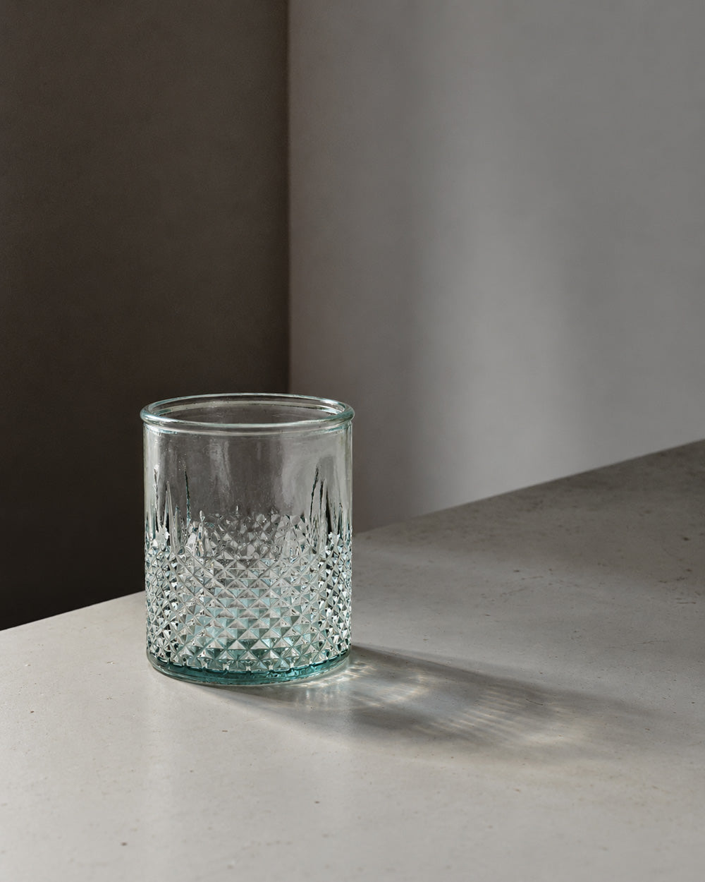 Facettiertes Trinkglas aus blauem Recyclingglas mit strukturiertem Boden