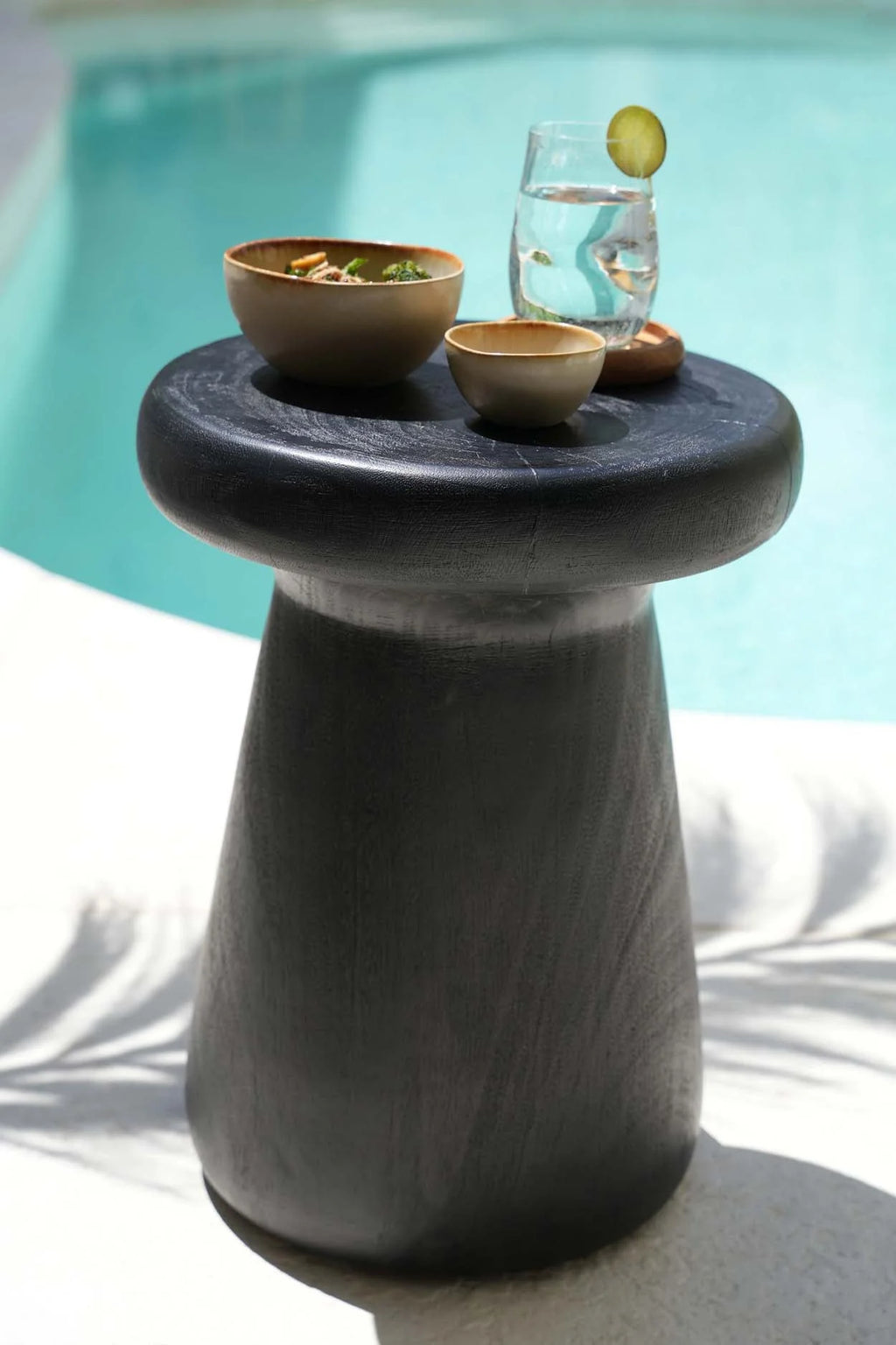 Table basse en pierre grise texturée, plateau rond et base effilée