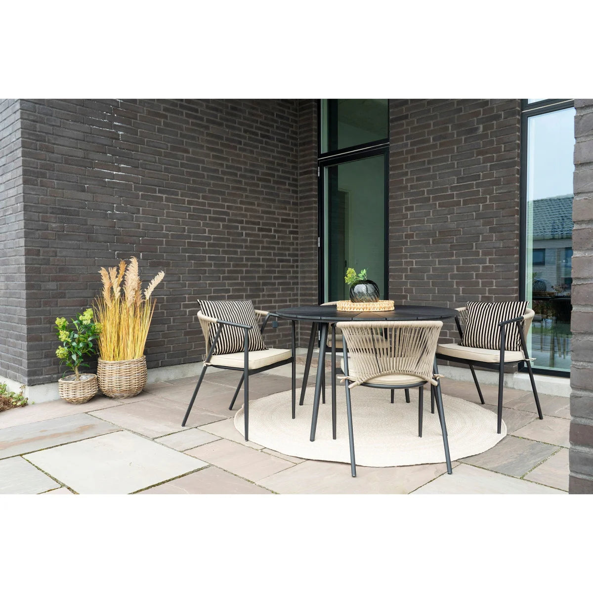 Table ronde noire en rotin avec coussins rayés et 4 chaises assorties