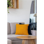 Coussin décoratif carré ocre texturé en coton recyclé sur canapé gris