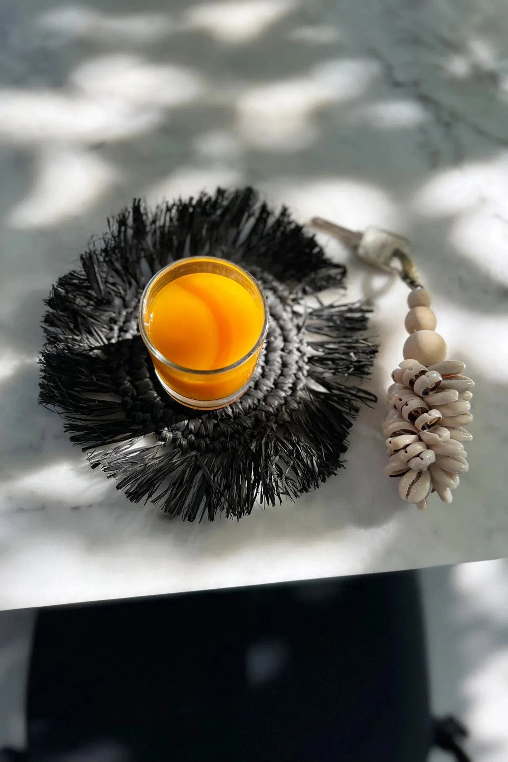 Verre de jus d’orange sur un dessous de verre rond en raphia noir avec franges