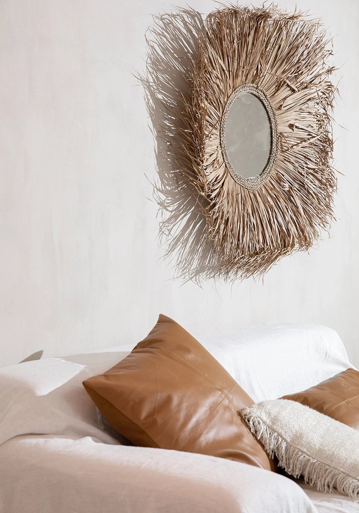 Miroir rond avec cadre en feuilles de palmier séchées naturel dans la pièce