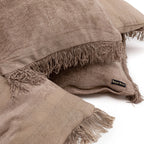 Coussins en lin marron empilés avec des bords effilochés pour Housse de coussin en velours côtelé beige