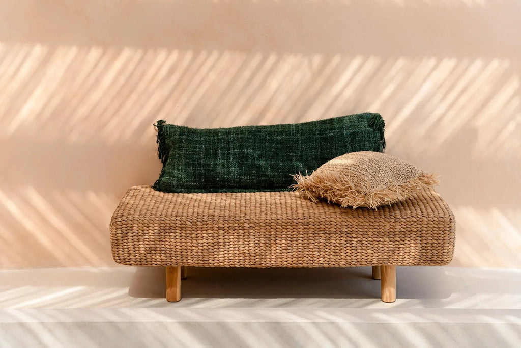 Banquette en rotin tissé avec deux coussins décoratifs verts forêt en coton