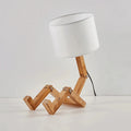 Vue de côté de la lampe de chevet bonhomme en bois avec abat-jour blanc