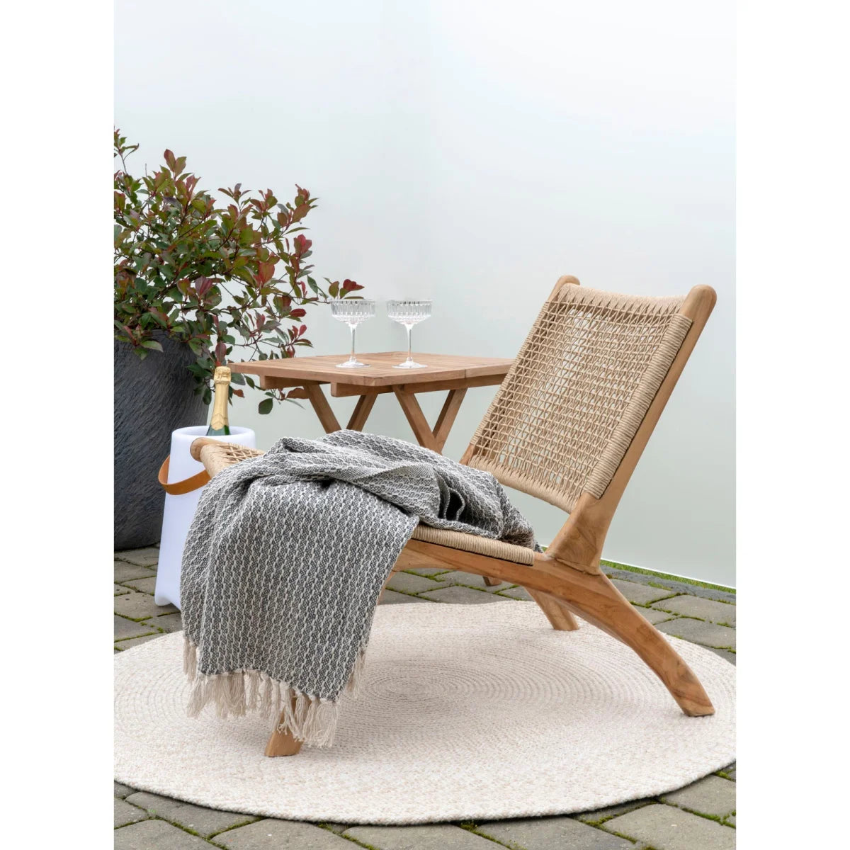 Chaise longue en bois clair avec dossier et assise en osier beige et plaid coton gris-beige frangé