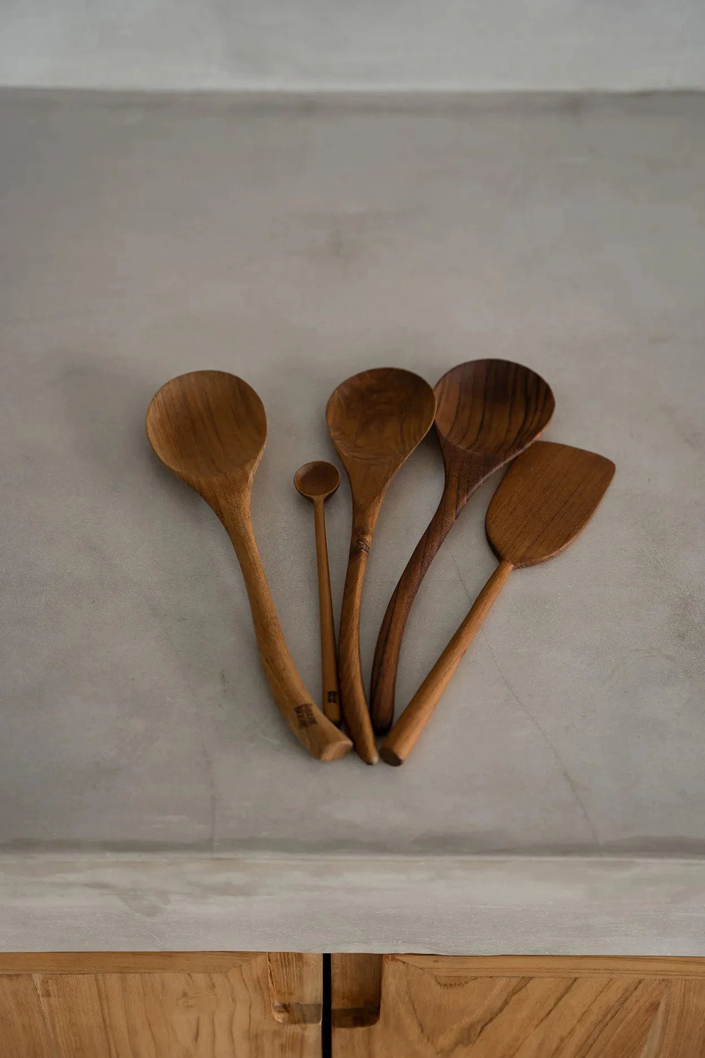 Collection de cinq ustensiles de cuisine en bois naturel, incluant une spatule en racine de teck de 28 cm