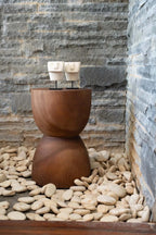 Tabouret en bois en forme de sablier avec deux petites sculptures abstraites de visage en grès Sumba