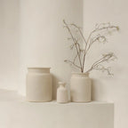 Trois vases céramiques beige minimalistes, un avec branches séchées